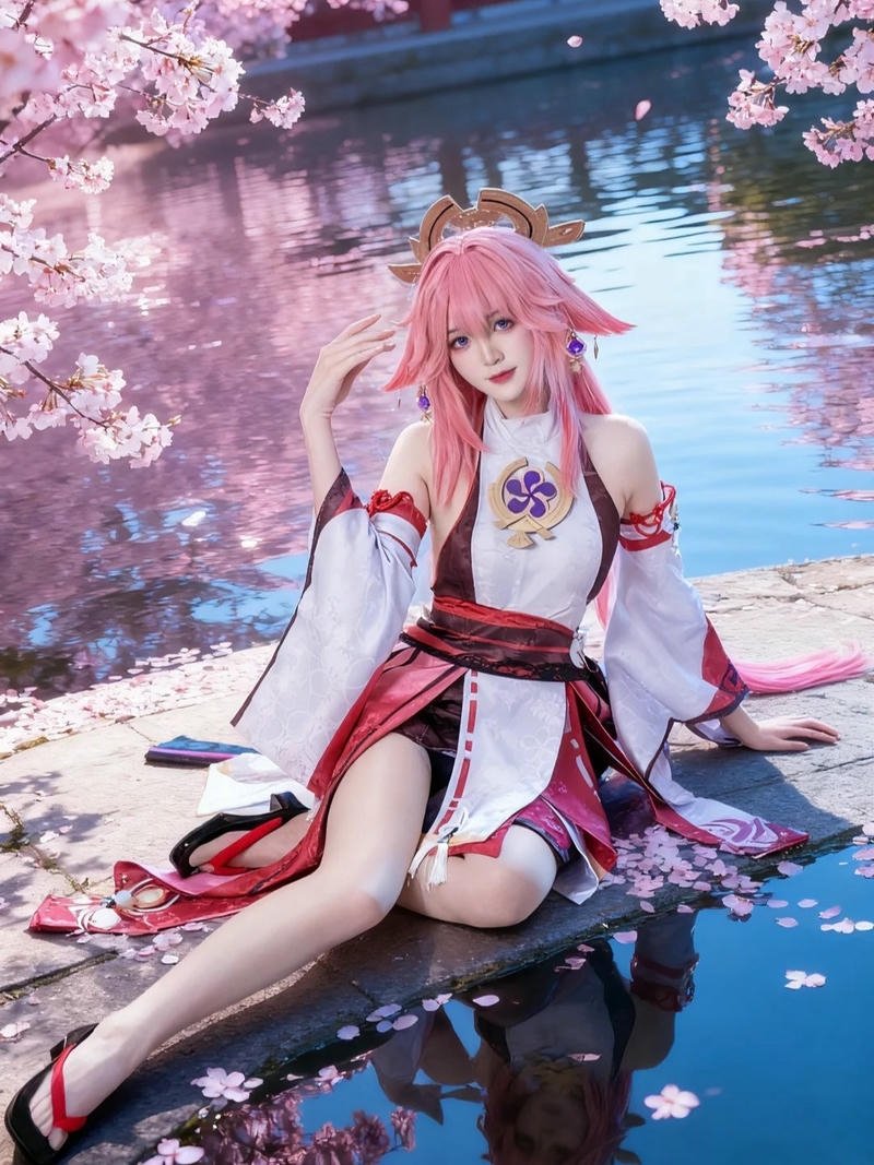 Yae miko cosplay ngồi bên hồ nước cánh hoa trôi nhẹ