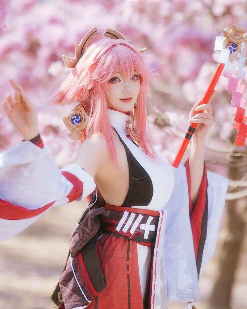 Yae miko genshin impact cầm gậy trừ tà nền hồng phấn